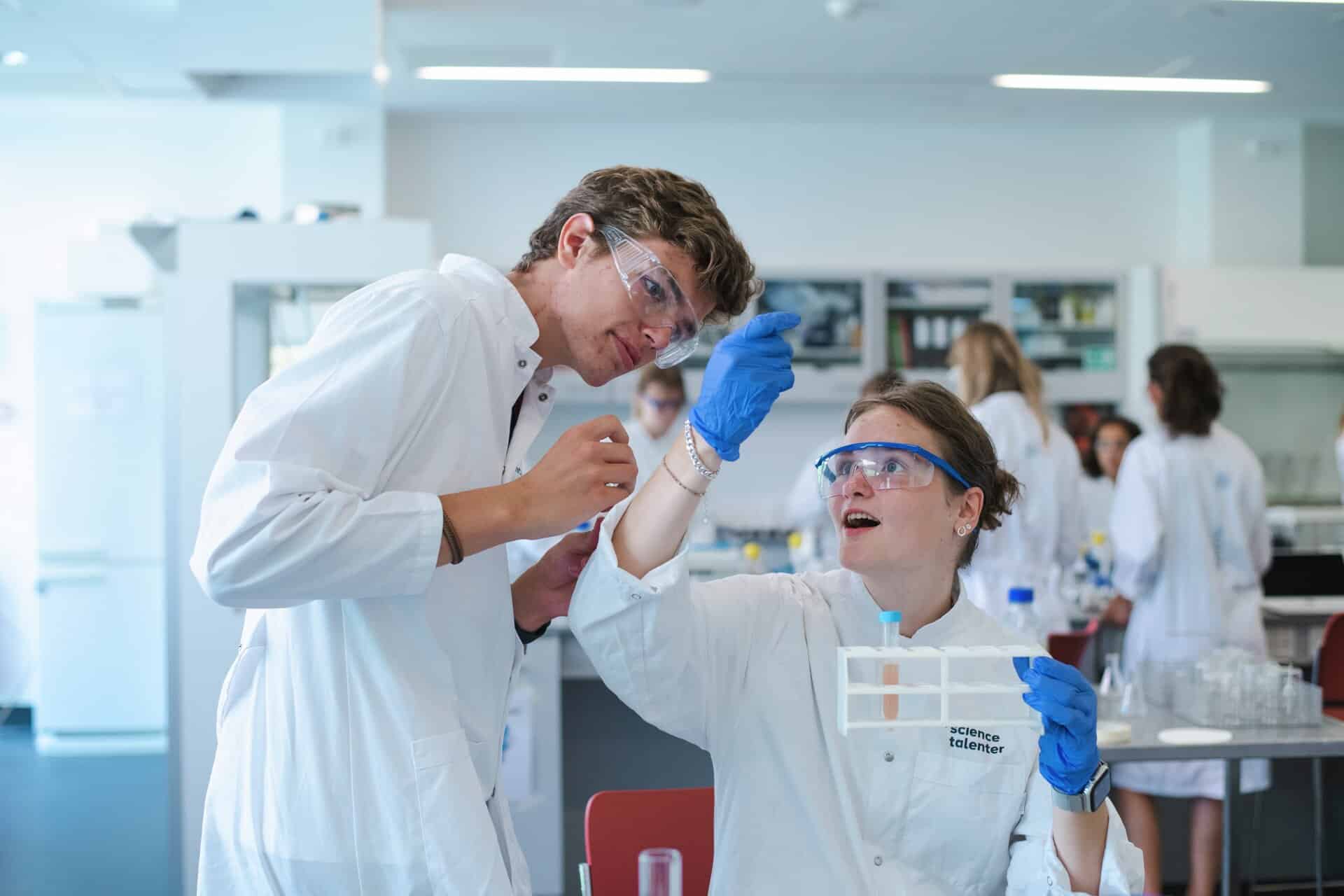 Elever i laboratoriekitler og med handsker inspicerer et reagensglas